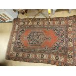 An antique Persian hand made Kurdi rug, the central medallion with ivory border on a red ground.