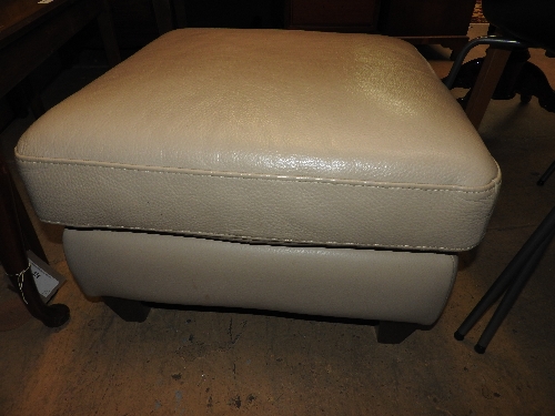 A contemporary designer footstool upholstered in ivory leather and raised on tapering supports