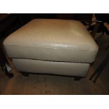 A contemporary designer footstool upholstered in ivory leather and raised on tapering supports