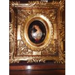 A miniature ceramic of a lady with candle in ornate gilt frame 20cm x 18cm