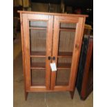 A pine bookcase with twin glazed panel doors on bracket feet. 
113cm x 70cm x 23cm.