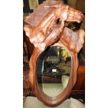 A 20th century oval wall mirror within an ornately carved wooden frame with a crest of two horse