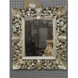 An ornately carved silvered framed mirror,