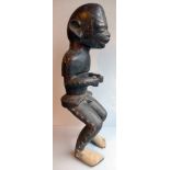 An antique carved wooden sculpture of a seated tribesman figure, H. 62cm.