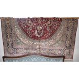 A Persian design silk rug with a floral medallion on an oval ground surrounded by one frieze and