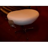 A contemporary designer footstool upholstered in ivory leather raised on chromed swivel supports
