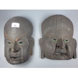 A pair of carved African tribal masks with painted detail