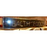 An illuminating neon shop sign 'HEALTH FOODS'