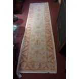 A hand knotted Pakistani woollen runner the beige and orange field decorated with flowerhead motifs