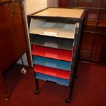 A retro metal filing chest of six trays raised on castors