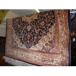 A Keshan style carpet with a medallion on a midnight blue field with ivory spandrels surrounded by