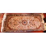 A Persian with silk rug, the beige field having extensive floral motifs and a central medallion,