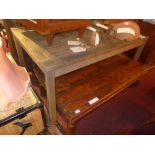 A weathered teak garden table of slatted construction.