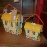 A pair of porcelain gypsy wagon form lidded buscuit barrells with swing handles
