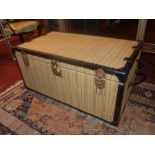 A vintage twin handled trunk clad in striped fabric and in leather binding