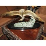 A gilt metal Art Deco period figure of a bird in flight on oval marble stand