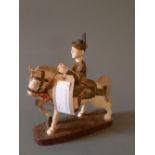 A carved and painted wood South East Asian figure of a soldier on horseback on an oval base.