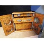 A late Victorian honey oak smoker's cabinet the twn panelled doors enclosing a fitted interior of