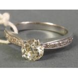 An 18k white gold diamond solitaire ring with diamond chip shoulder,