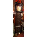 An early 19th century carved oak and mahogany long case clock with circular engraved brass Roman