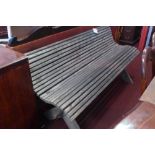 A weathered teak garden bench of slatted construction