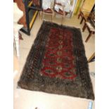 A Bokharra rug, the all over geometric design on ruby ground within wide turquoise banded borders,