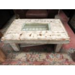 A rustic painted white coffee table with glass insert