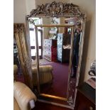 A French style pier mirror having floral crest and divisional bevelled plates in a gilt frame.