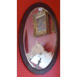 An Edwardian oak oval wall mirror with bevelled plate.