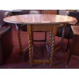 A 1940'S light oak drop flap dining table with twin oval flaps raised on barley twist gateleg