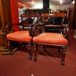 A pair of 19th Century mahogany elbow chairs with stuffover seats upholstered in red fabric,
