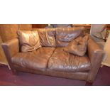 A contemporary designer two seater sofa of angular form upholstered in brown leather on chromed