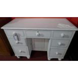 A white painted pine kneehole desk fitted seven drawers and raised on turned supports.