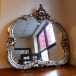 A Rococo style wall mirror with ornate swept and slivered frame