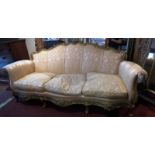 A French carved giltwood three seater sofa upholstered in gold floral and striped damask on