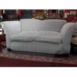 An Edwardian two seater drop end sofa upholstered in beige checkered wool fabric and raised on