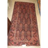 An antique belouch rug, the all over geometric design on ruby ground,