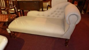 A contemporary chaise long upholstered in buttoned ivory linen and raised on turned supports