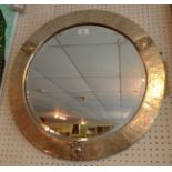 A 20th Century looking glass the circular bevelled plate within silvered brass planished frame.