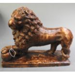 A bronzed model of a lion reclining on a