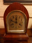 An Edwardian oak bracket clock with silvered dial within a lancet form case on squat ban feet.