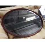 An Edrwardian mahogany and inlaid oval mirror, and another shaped mirror,