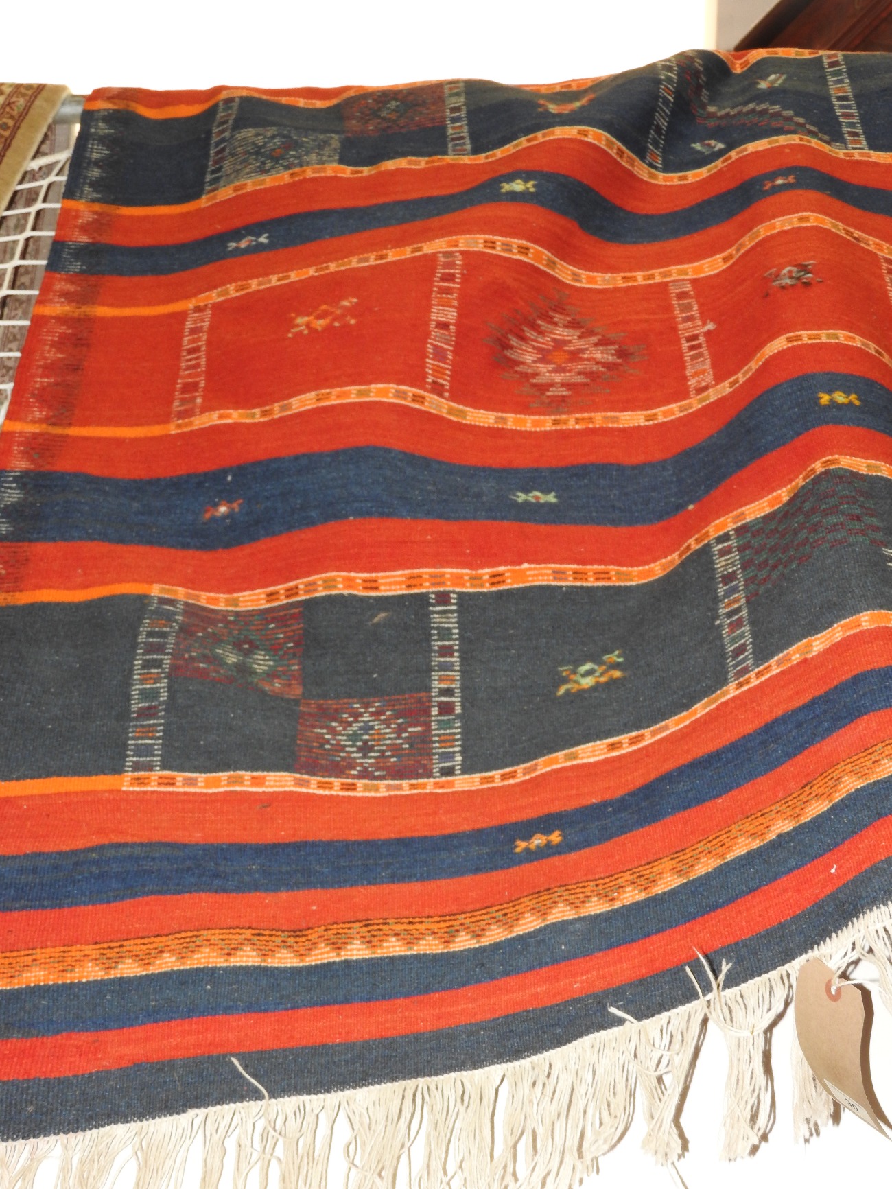 A Turkish Kilim rug, the all over geometric design on a ground of red and blue bands.