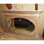 An oval overmantle mirror with bevelled place within distressed frame.