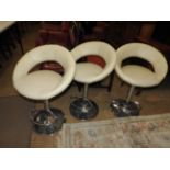 A set of three contemporary bar stools the cream leather bucket seats raised on adjustable chrome