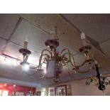 A brass Dutch style eight branch chandelier with ceramic detail decorated with flowers.