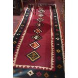 A fine south west Persian Qashgai Kilim 335cm x 130cm a repeating row of medallion on a rouge field