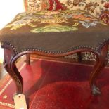 A Victorian walnut stool upholstered in foliate tapestry fabric and raised on cabriole supports.