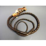 A long plaited leather horse whip with two tone leather handle