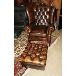 A golden brown leather button wingback armchair with matching stool